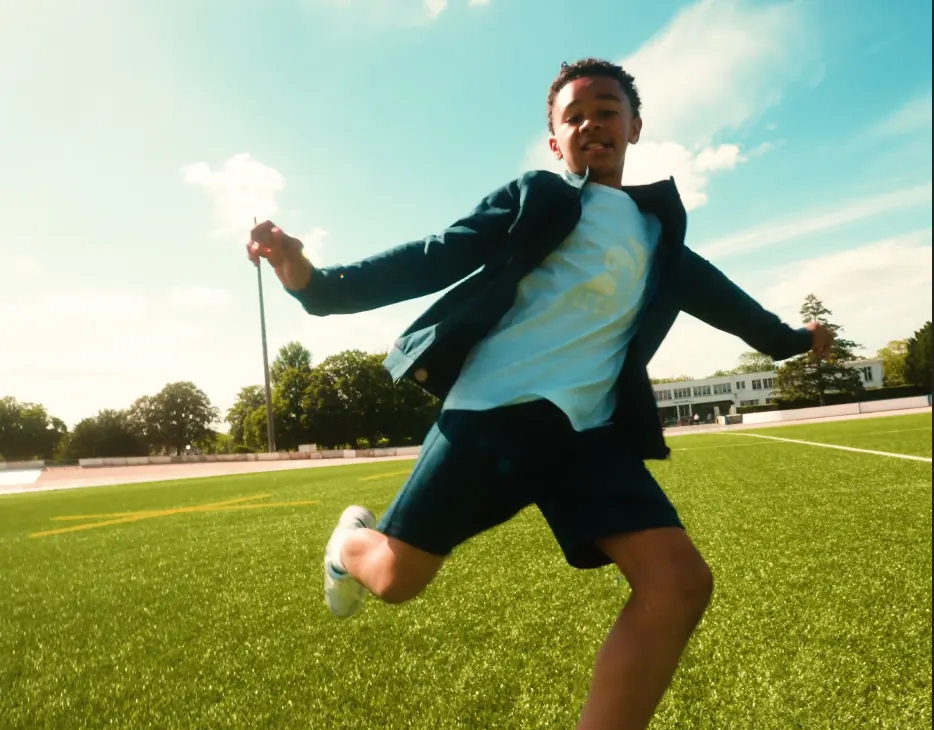 Jeune footballeur frappant le ballon sur la pelouse d’un stade, en contre-plongée