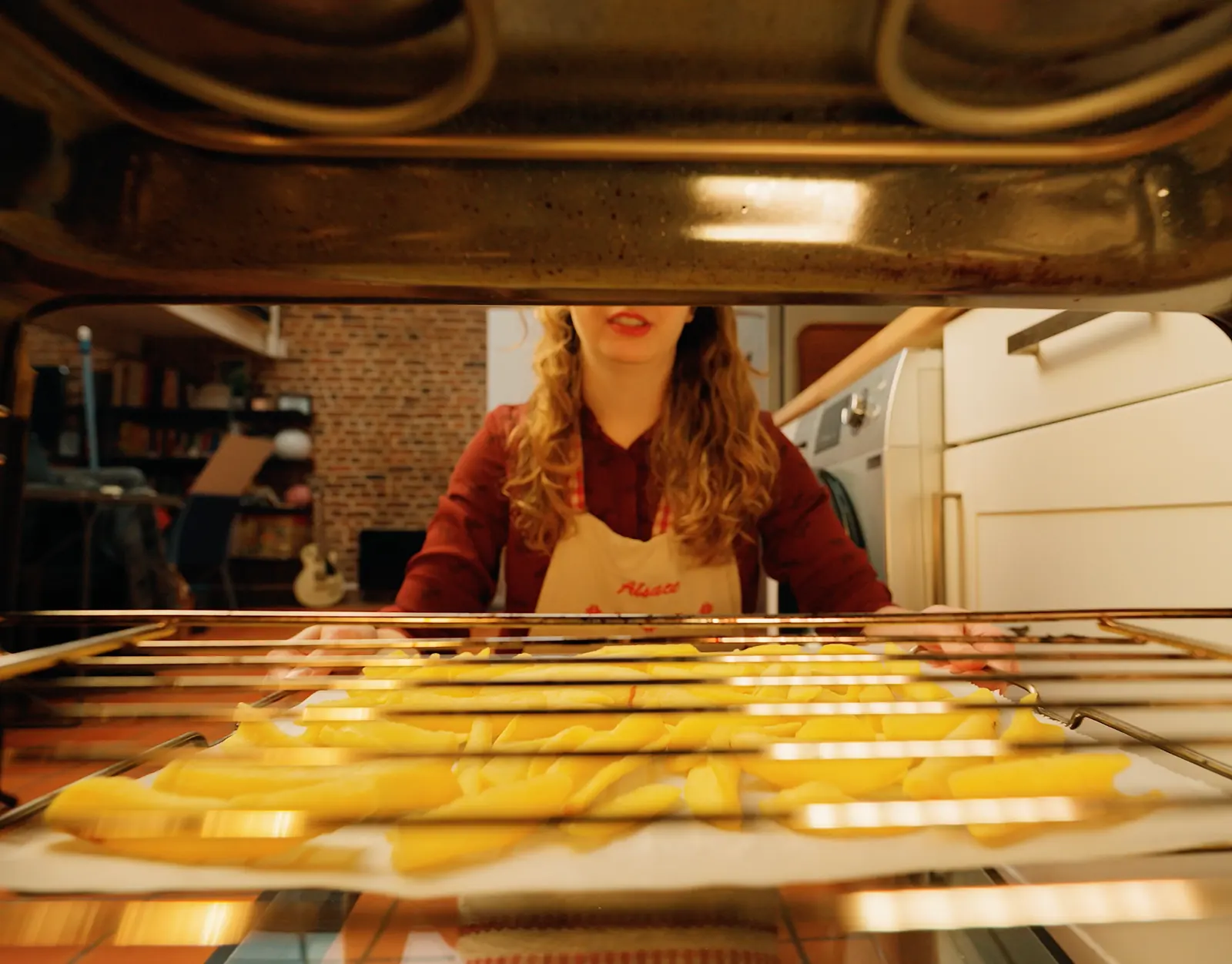 Frites dorées sur une plaque de four, une cuisinière en arrière-plan